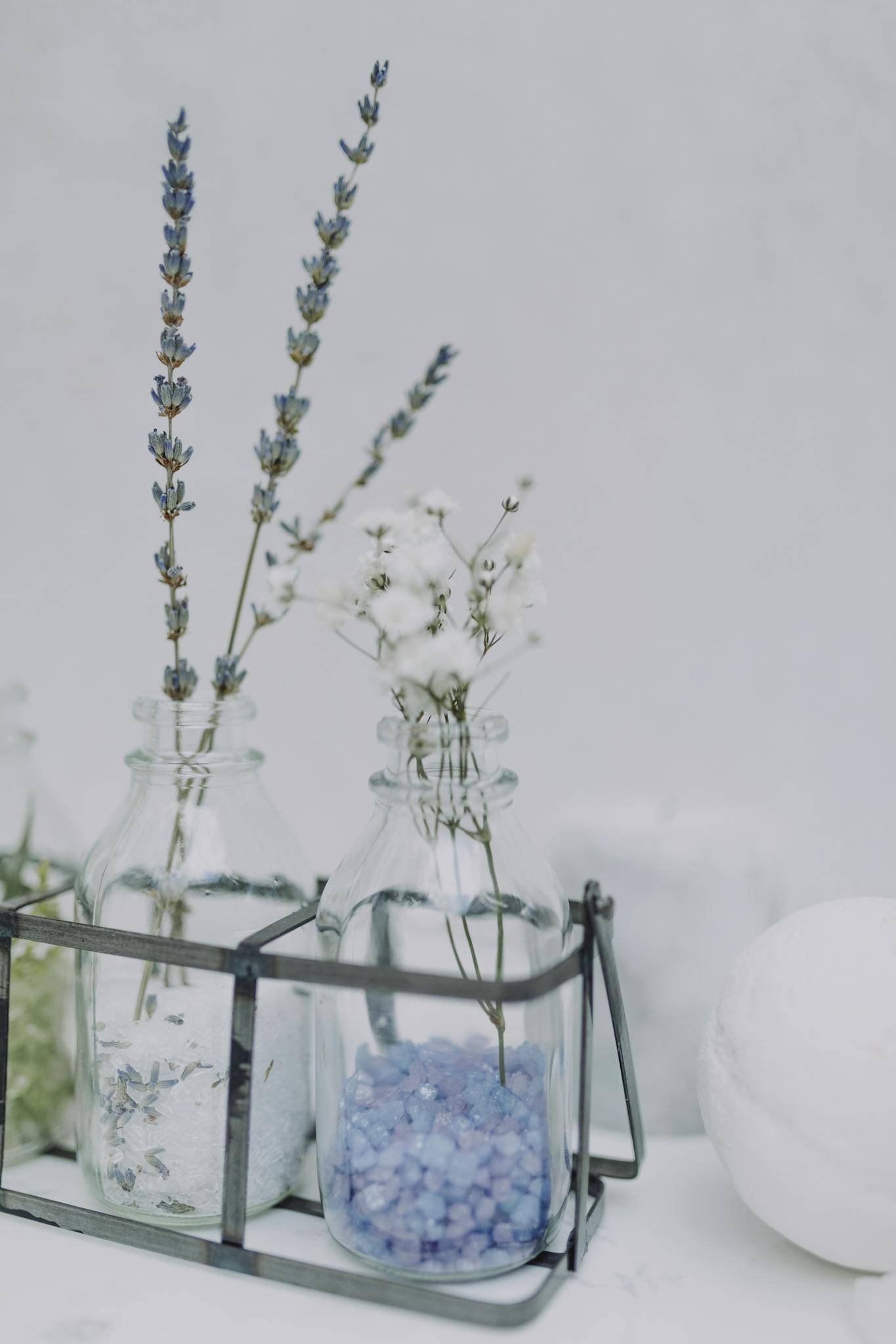 Elegant glass bottles with lavender flowers and blue bath salts for a serene spa atmosphere.