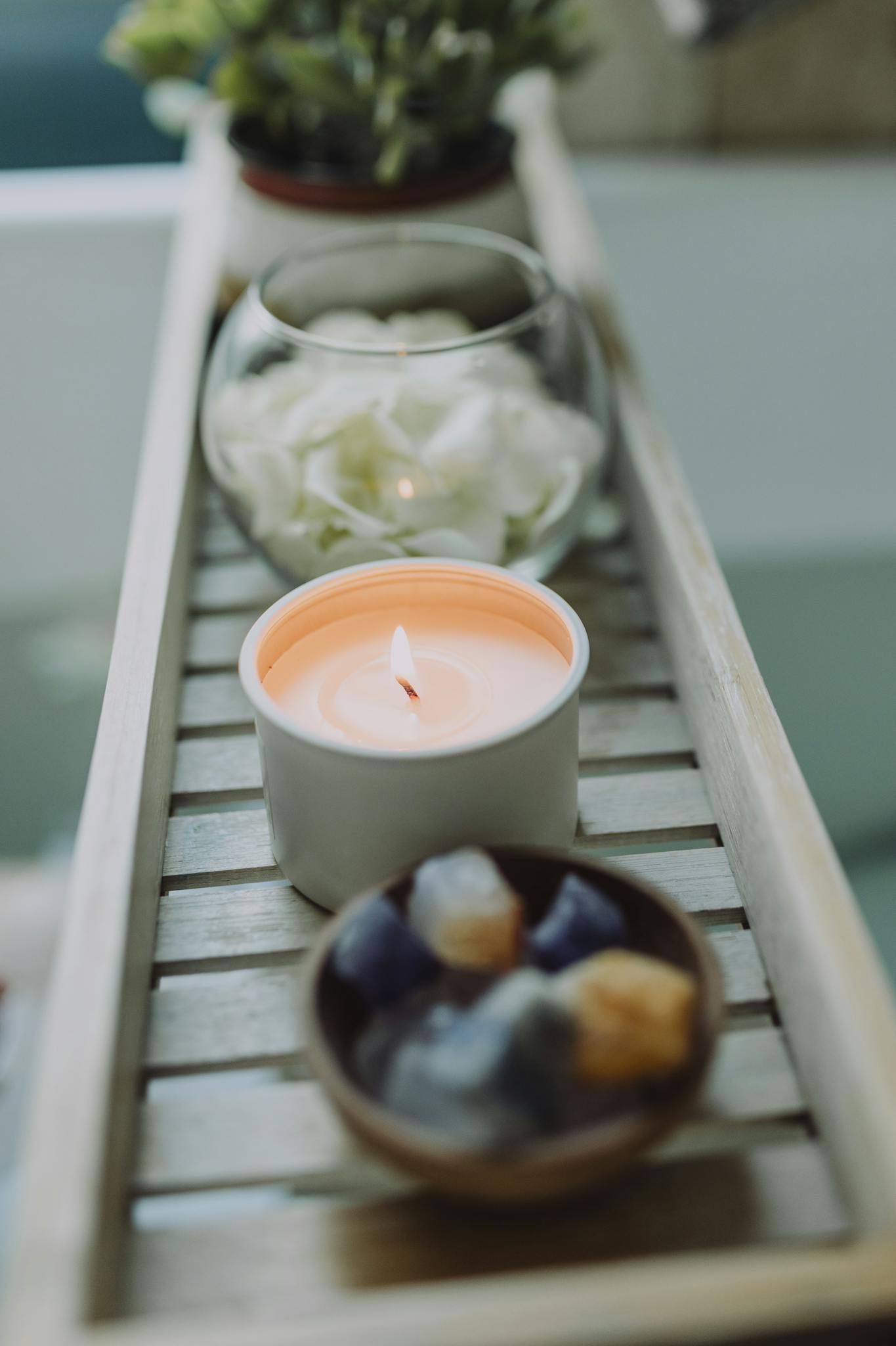 Peaceful spa setup with lit candle and healing crystals on a wooden tray.